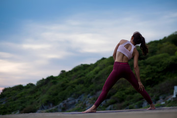Rear view of healthy women practicing standing and stretching pose.  standing twisting pose. yoga landscape on evening view on evening nature evening outdoor, concept for exercising, health care