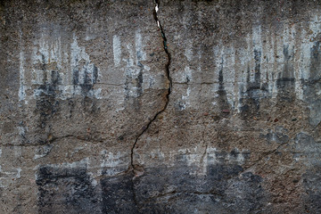 old concrete wall with deep crack, texture background, white black traces of paint