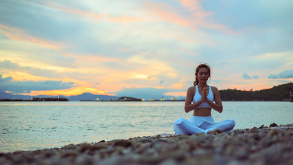 Fototapeta na wymiar Healthy women practicing yoga. sitting in lotus pose meditation outdoors concentrating breathing asana yoga.Easy Pose. .landscape view sky on morning outdoor near sea