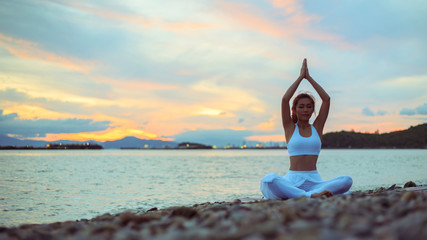 Young woman practicing yoga. sitting in Sukhasana exercise. Easy Seat pose.  .beautiful landscape...