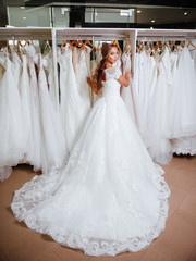 Back view of a young woman in wedding dress looking at bridal gowns