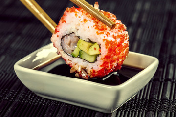 sushi roll dipped in soy sauce