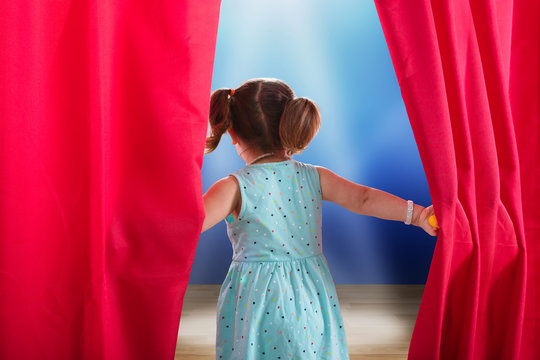Girl Peeking Through A Stage Curtain