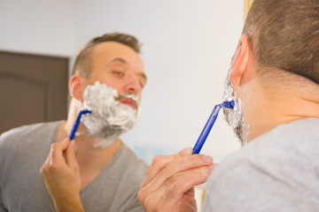 Guy shaving his beard in bathroom