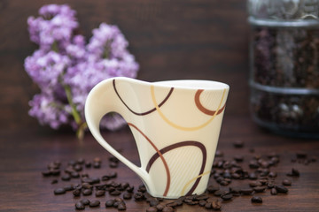Coffe Cup with Spreading Coffee Beans and Coffee Container and Lilac Flower