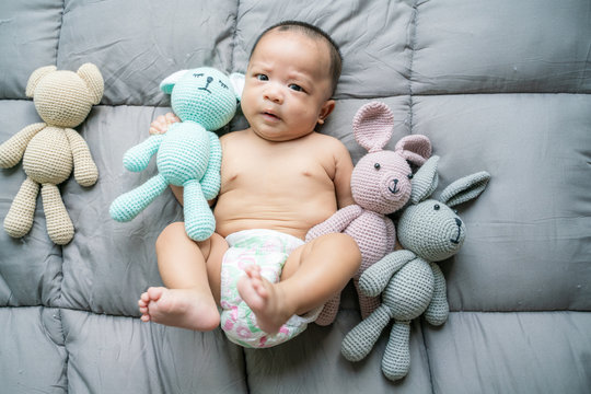 Adorable asian boy lying on bed with many doll