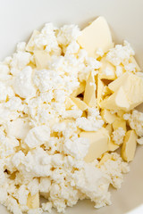 In a mixing bowl are the ingredients butter and cottage cheese for making cookies