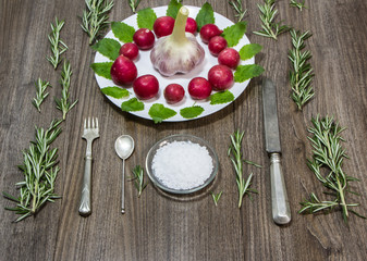 composition with radishes, garlic, sea salt, rosemary, lemon balm, silver cutlery