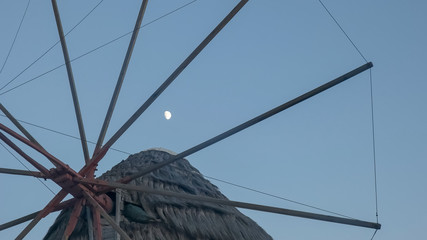 Fototapeta premium the moon and a close up of the historic windmills on mykonos