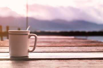 Cup of coffee on the wood birdge with mountain view background.