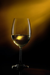 Glass filled with white wine on a gradient background. Close-up studio shot.