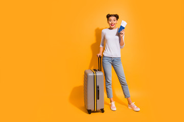 Full length body size portrait of cheerful satisfied student prepared for long trip voyage holding suit-case documents in hand isolated over bright background in light pullover blue jeans