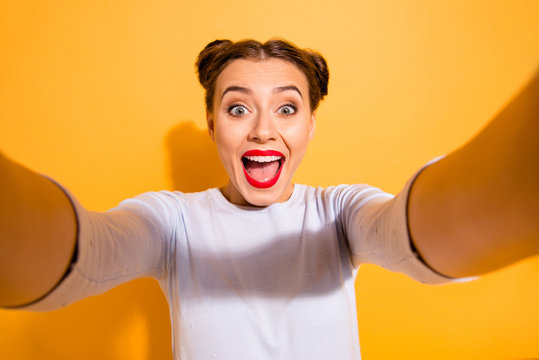 Close up photo of cute funny cheerful shocked childish lady taking photos impressed by incredible news with positive mood has her mouth open dressed in white sweater isolated over yellow background 