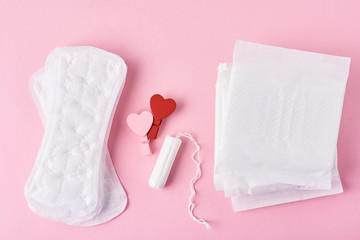 Sanitary pad, menstrual tampon and wooden red heart on a pink background,top view