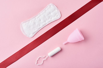 Sanitary pad, menstrual cup and tampon on a pink background
