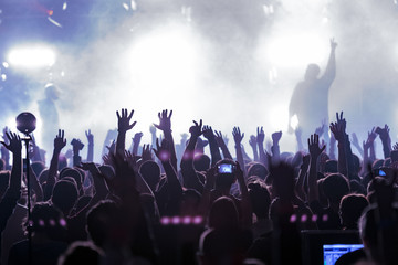 concert, silhouettes of happy people raising up hands, Music show. Bright scene lighting in club....