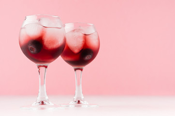 Fresh summer blueberry homemade lemonades in two goblets with ice cubes, berry in elegant pastel pink color kitchen interior, copy space.