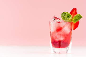 Fresh summer strawberry homemade cocktail in shot glass with ice cubes, strawberry slice, green...