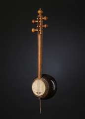 ancient Asian stringed musical instrument on black background with backlight