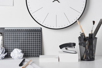 Office supplies and wall clock on white