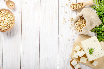 Soy Bean curd tofu on cutting board and in hemp sack on white wooden kitchen table. Space for text