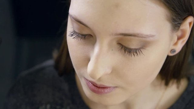 The girl's face close-up, which is prepared to paint the eyebrows. Wipe her eyebrows with a cotton pad.