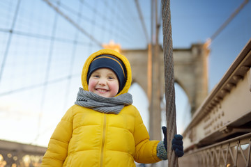 Cute little boy on Brooklyn Bridge with skyscrapers on background