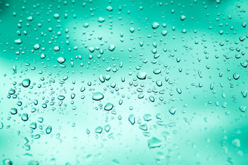 Raindrops splatter on the glass of car window. View through car window green blurred with heavy rain.