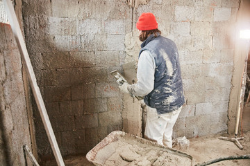 Real construction worker making a wall inside the new house.