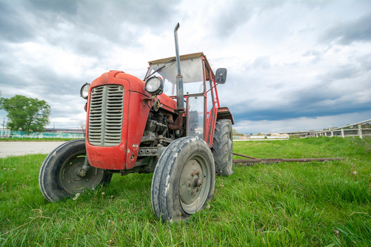 An old and abandoned tractor sitting in the field, broken and unused