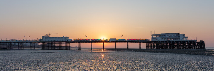 Fototapeta na wymiar Dawn With Sun Rising Behind Worthing Pier at Low Tide