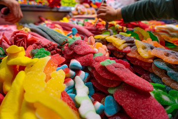 People taking various colorful candies and jellies in the marketplace