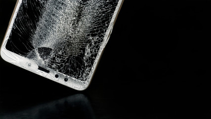 Modern smartphone with highly broken screen on black background. Copy space.