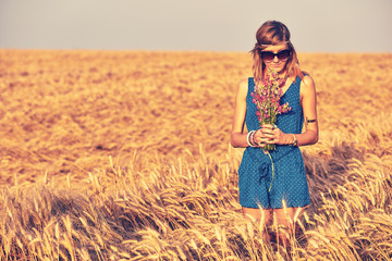 Woman with bouquet of flowers in a wheat field.