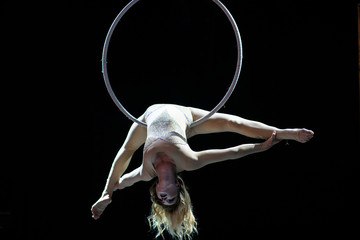 Graceful aerial acrobat doing her performance with a hoop isolated on black