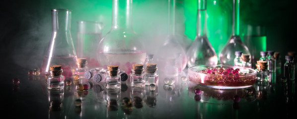 Pharmacy and chemistry theme. Test glass flask with solution in research laboratory. Science and medical background. Laboratory test tubes on dark toned background