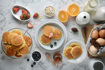 A stack of pancake with blueberries, strawberries, orange on white marble table. Breakfast menu, top view