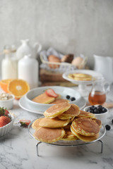 A stack of pancake with blueberries, strawberries, orange on white marble table. Breakfast menu, top view