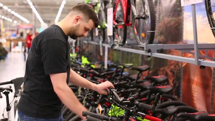 Handsome man is looking to buy new bicycle in the store. Sportsman wants to buy new mountain bike.