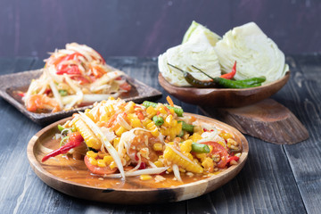 corn and papaya salad on wooden plate Thai style