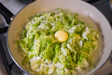 Cooking. Pie stuffing - braising cabbage in frying pan on a stove. Sauteing. Selected focus, narrow depth of field.