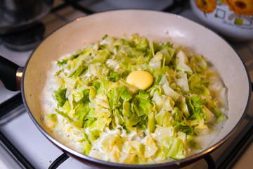 Cooking. Pie stuffing - braising cabbage in frying pan on a stove. Sauteing. Selected focus, narrow depth of field.