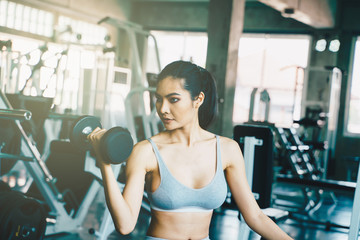 Wellbeing smart asian sport women lifting dumbbell in gym