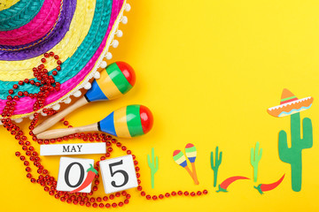 Fototapeta na wymiar Mexican hat with maracas, cube calendar and paper cactuses on yellow background