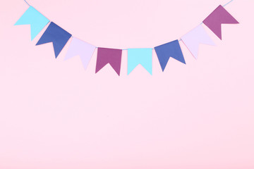 Colorful paper flags hanging on pink background