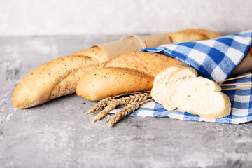 Fresh baguettes with wheat ears on grey wooden table