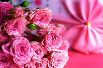 A bouquet of roses and a gift on a pink background