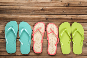 Pairs of colorful flip flops on brown wooden table