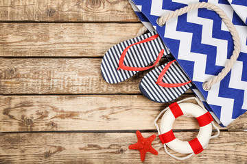 Pair of flip flops with starfish and lifebuoy on brown wooden table