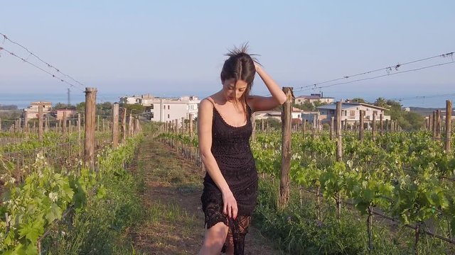 Ragazza giovane con vestito elegante nero in campagna in mezzo ai vigneti.